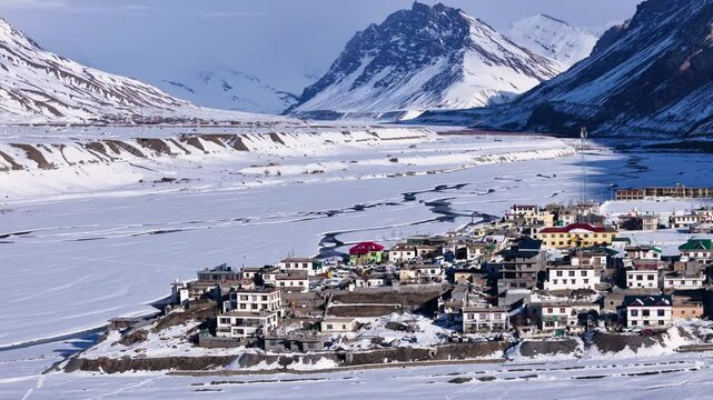 Aerial drone shot highlighting the serene beauty of Kaza in winter, as the sun&rsquo;s rays add warmth to the frozen streets and icy mountain slopes.