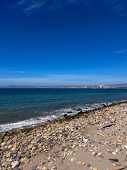 Rocky Beach Shoreline with Ocean Waves and Distant City View