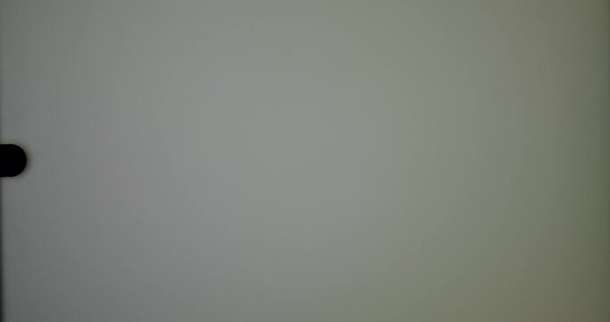 A blurred silhouette of a person seen through a frosted glass door, evoking a sense of mystery and suspense in a subdued setting.