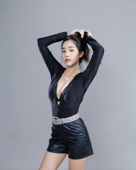 Asian Thai woman in black outfit holding hair up and looking confident
