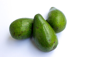 Three unripe avocado fruits on white background.