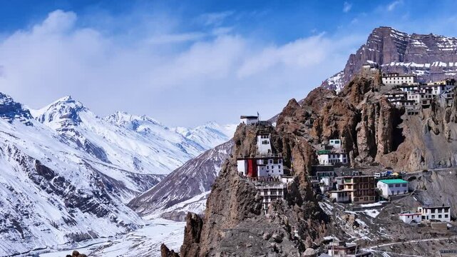 Aerial drone shot displaying the winter beauty of Dhankar Monastery, where prayer flags flutter against the stark white backdrop of snow-covered peaks.