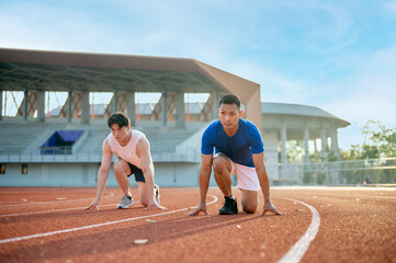 Two asian athlete men in a crouch start or starting position ready to run on the racetrack.