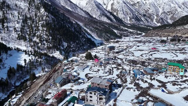 Aerial drone shot capturing the peaceful winter ambiance of Chitkul, as the golden sunlight casts a soft glow over the untouched snowfields and distant peaks.