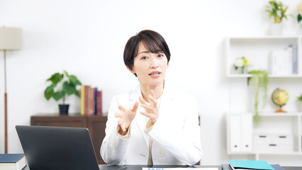 カメラ目線で会話する白衣のミドル女性