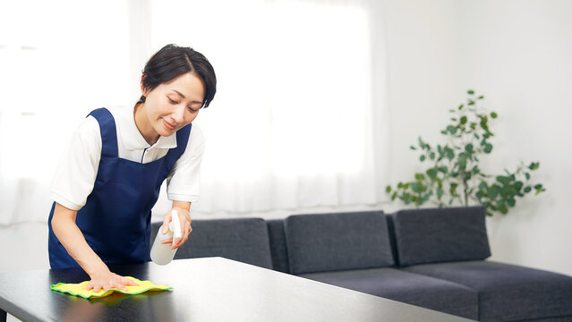 部屋を掃除するエプロンをつけたミドル女性