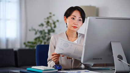 暗いオフィスでパソコンを使って作業する女性ビジネスパーソン