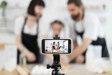 Caucasian adults with child creating cooking content for blogging during energetic photo session at home