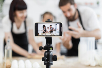 Caucasian family composing cooking tutorial recording video in bright home kitchen showing baking...