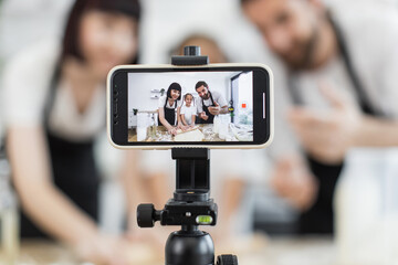 Caucasian parents and young daughter creating content as bloggers by kneading dough together....