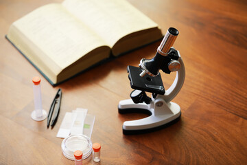 Microscope on Wooden Table with Open Book and Scientific Equipment for Research