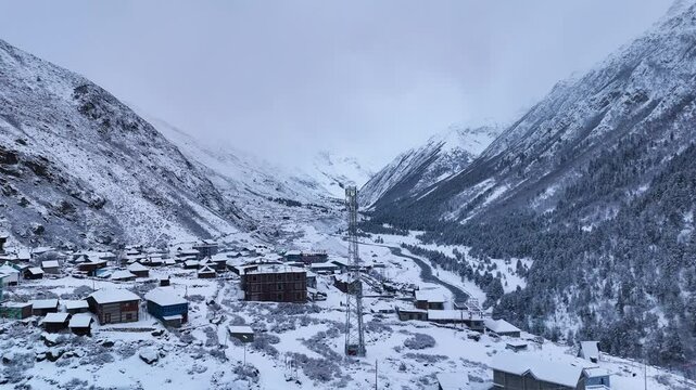 Aerial drone footage showcasing Chitkul in peak winter, where deep snow covers houses, roads, and trees, blending into the surrounding Himalayan peaks.