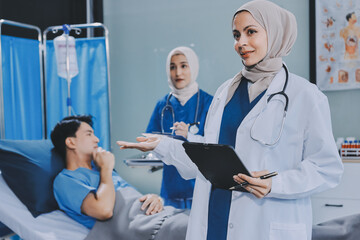 Obraz premium A young man lies on a bed in a hospital ward talking with her young Indian doctor. Doctor checking patient's health doctor treating patient, hospital admission of patient