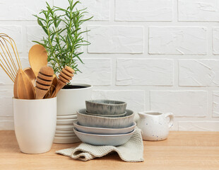 Kitchen utensils, rosemary plant, and ceramic bowls creating a cozy kitchen atmosphere