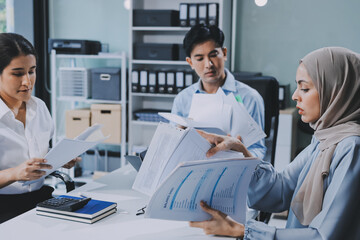 Obraz premium Young asian businesswoman suffering from headache while colleagues arguing and blaming her for bad work results during stressful office meeting
