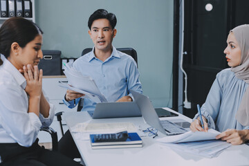 Young asian businesswoman suffering from headache while colleagues arguing and blaming her for bad...
