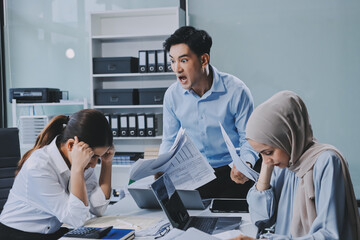 Young asian businesswoman suffering from headache while colleagues arguing and blaming her for bad...