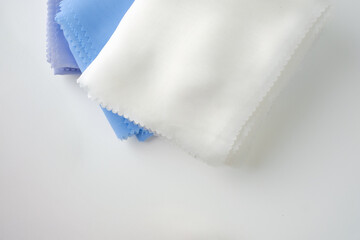Stack of pastel-colored plain hijabs in light blue, white, and lavender on a clean white background. Elegant and minimalist look, perfect for Muslim fashion catalog