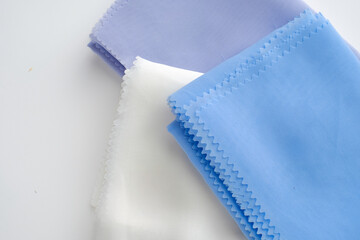 Stack of pastel-colored plain hijabs in light blue, white, and lavender on a clean white background. Elegant and minimalist look, perfect for Muslim fashion catalog