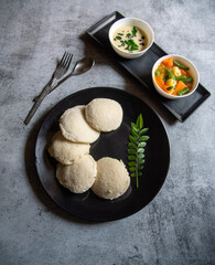 South Indian staple food steamed idli served on a plate with condiments. 