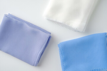 Stack of pastel-colored plain hijabs in light blue, white, and lavender on a clean white background. Elegant and minimalist look, perfect for Muslim fashion catalog