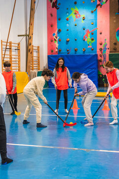 Group of elementary school students playing floorball together in a gym class, promoting teamwork, coordination, and physical activity