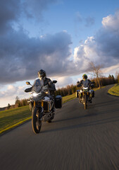 Drivers riding motorcycle on empty road during sunset, spring mountains