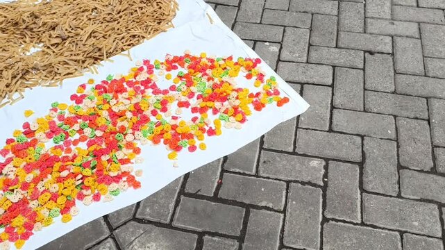 Raw unfried crackers are spread across white trays and left to dry naturally under sunlight before frying.