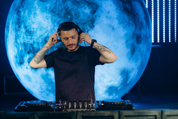 Professional DJ Performing on Stage With Modern Equipment and Artistic Lighting Setup