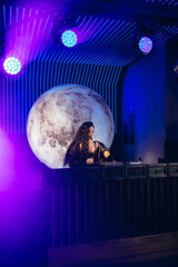 Female DJ Performing At Nightclub With Neon Lights And Planetary Decoration
