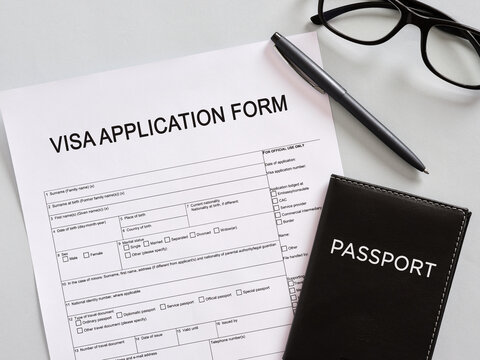 Filling visa application form with passport and pen