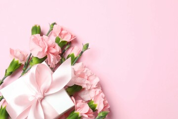 Beautiful bouquet of pink carnations with gift box on a colored background