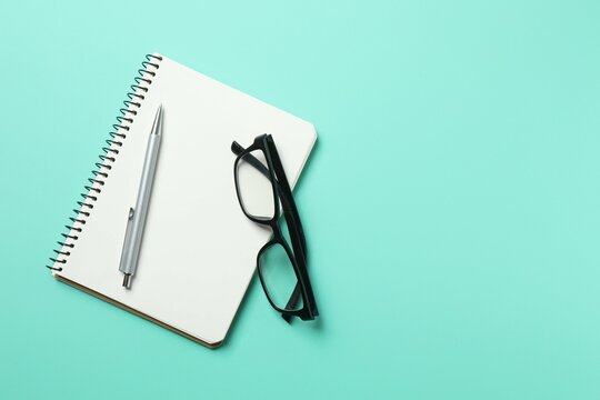 Top view photo of notebook with a pen and glasses on color background with blank space. Business concept - Powered by Adobe