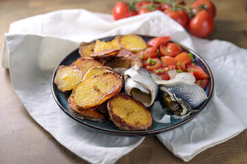 Rollmops, German dish from rolled pickled herring fillets, with fried potatoes and tomatoes, traditional food against hangovers, copy space, selected focus