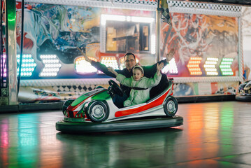 Father and daughter enjoying bumper cars at amusement park