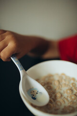 A spoon is being used to eat cereal. The spoon has a cute animal design on it