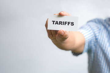 Man holding a white card with Tariffs message.