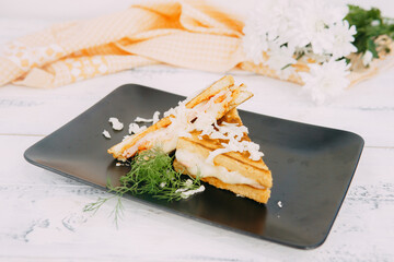 A close-up of a delectable grilled sandwich decorated with shredded cheese and fresh herbs, set...
