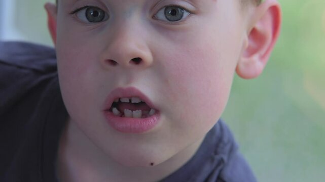 A detailed closeup of a young boy displaying a wonderfully curious expression, showcasing his missing teeth