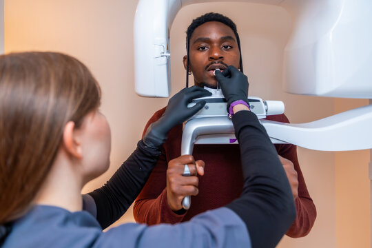 Dentist positioning patient for dental x ray scan in modern clinic