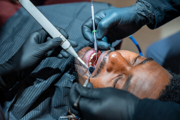 Obraz premium Dentist performing teeth whitening procedure on patient in clinic