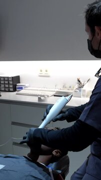 Dentist using an intraoral scanner on patient in modern dental clinic, creating digital model of teeth