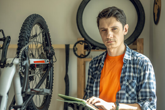 A male bicycle mechanic repairs a mountain bike in a workshop. The concept of preparation for the new season, repair and maintenance