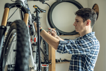 A male bicycle mechanic repairs a mountain bike in a repair shop. The concept of preparation for the new season, repair and maintenance