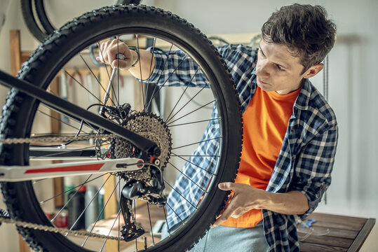 A male bicycle mechanic in the repair shop disassembles a mountain bike and repairs it. Maintenance concept, preparation for the new season