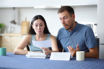 Perplexed interracial couple reading bank statement