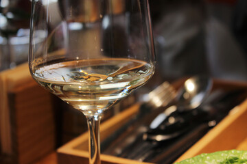 A glass of white wine stands on a table in a restaurant