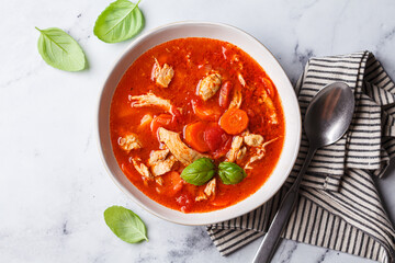 Tomato chicken soup with vegetables and basil.