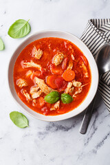 Tomato chicken soup with vegetables and basil.