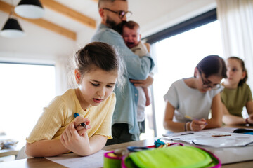 Fototapeta premium Father helping his daughters with homework while taking care of baby.